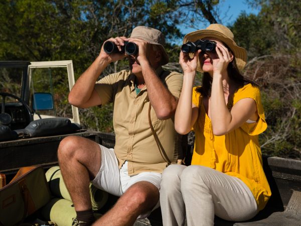 Couple looking through binoculars while sitting in vehicle