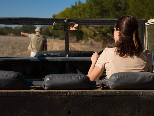 Rear view of man seen through windshield with woman driving off road vehicle on landscape