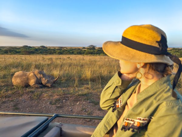 Safari holiday. Blond woman watching african elephants from roof of a safari car. Family on safari holiday in Amboseli national park. Wildlife photography in Kenya, Tanzania.