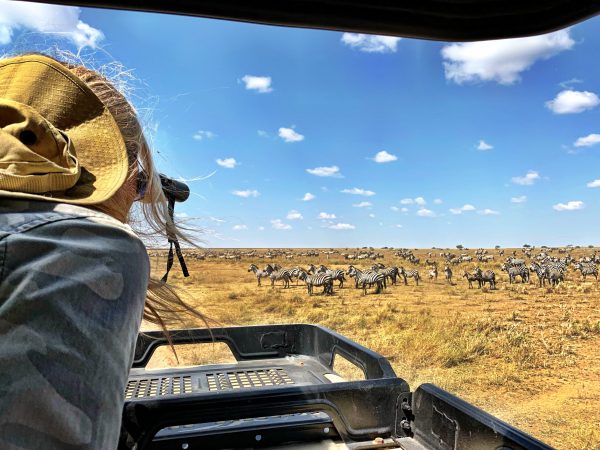 woman-looking-through-binoculars-vehicle-against-zebras-serengeti-national-park