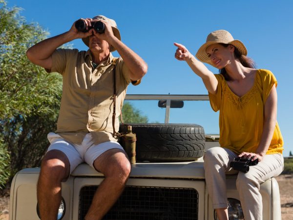 Woman with man pointing while sitting on off road vehicle hood